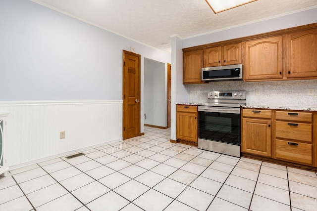 kitchen with backsplash, crown molding, brown cabinets, appliances with stainless steel finishes, and a textured ceiling