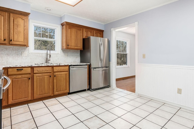 kitchen featuring a sink, stainless steel appliances, brown cabinets, and a healthy amount of sunlight