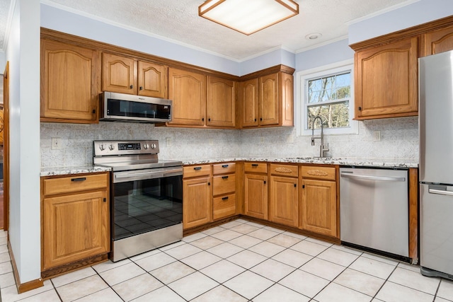 kitchen featuring a sink, stainless steel appliances, light stone counters, and brown cabinetry