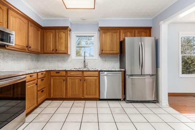 kitchen with a sink, plenty of natural light, brown cabinets, and stainless steel appliances