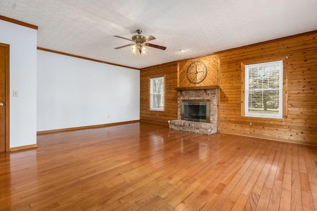 unfurnished living room with a textured ceiling, ornamental molding, light wood-type flooring, and ceiling fan