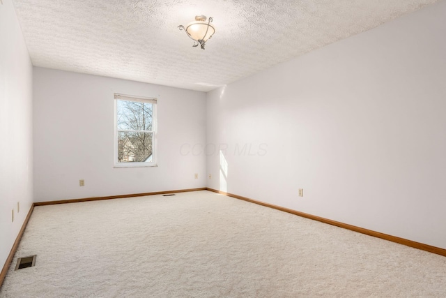 carpeted spare room with visible vents, a textured ceiling, and baseboards