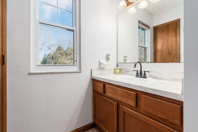 bathroom featuring vanity, plenty of natural light, and baseboards