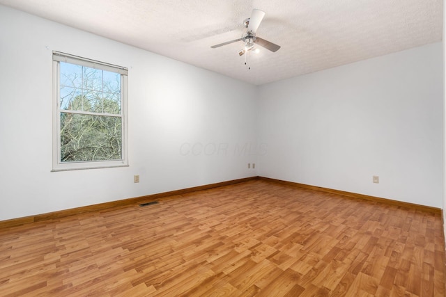 empty room with visible vents, baseboards, light wood-type flooring, a textured ceiling, and a ceiling fan