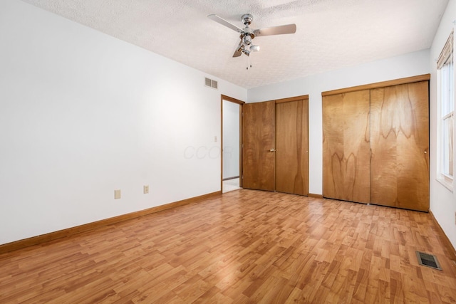 unfurnished bedroom with visible vents, multiple closets, and light wood-style floors