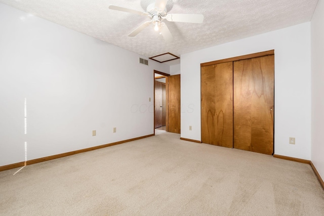 unfurnished bedroom with light carpet, visible vents, a textured ceiling, and baseboards