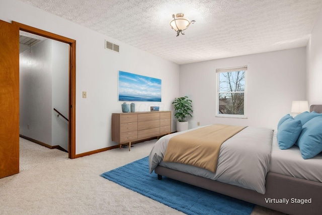 bedroom with visible vents, baseboards, light colored carpet, and a textured ceiling