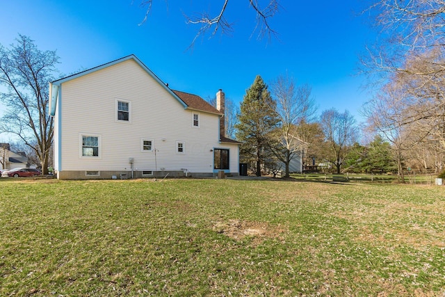 rear view of house featuring a yard and a chimney