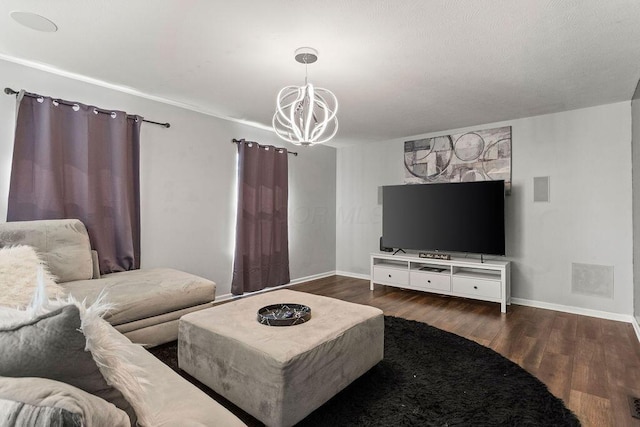 living area with visible vents, wood finished floors, baseboards, and a chandelier