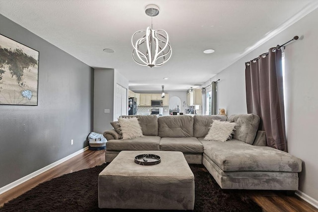 living room featuring dark wood-style floors, baseboards, and an inviting chandelier