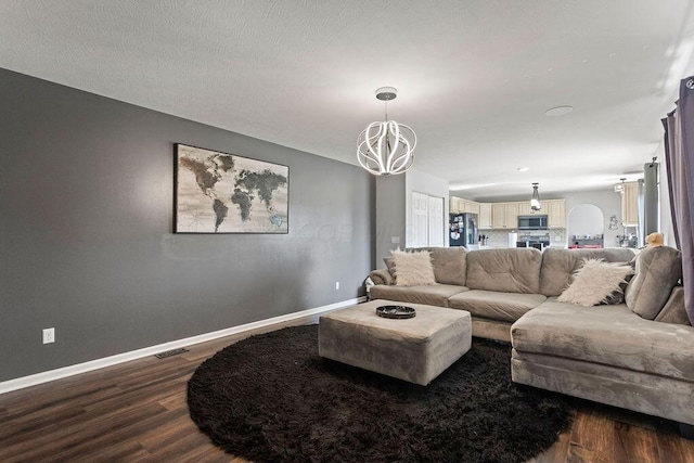 living room featuring a notable chandelier, baseboards, dark wood-type flooring, and visible vents