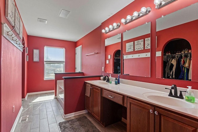 bathroom with double vanity, wood finish floors, visible vents, and a sink