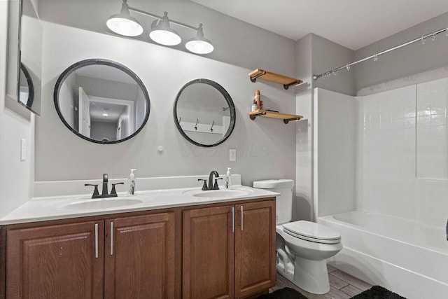 bathroom featuring double vanity, shower / bath combination, toilet, and a sink