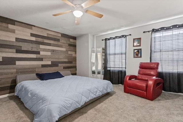 bedroom featuring an accent wall, a ceiling fan, wood walls, and carpet floors