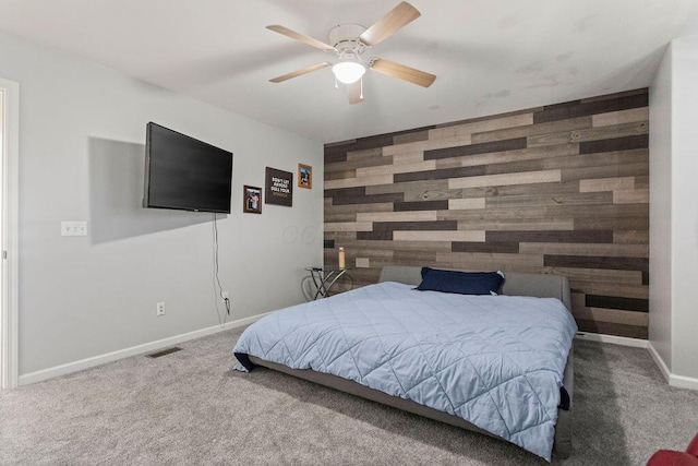 bedroom with an accent wall, wooden walls, carpet, and baseboards