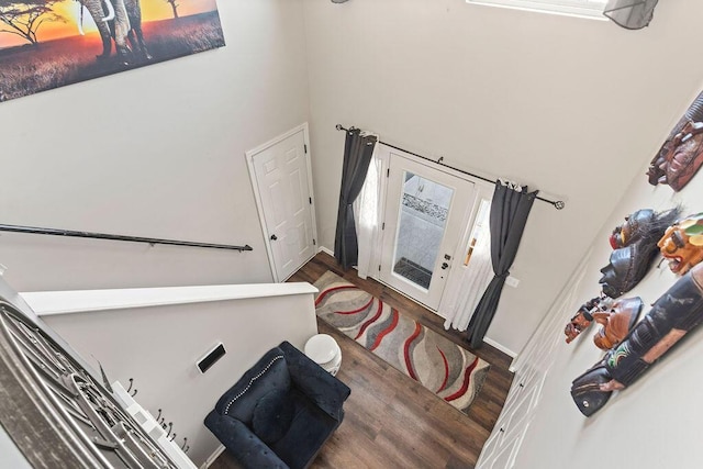 interior space featuring baseboards, wood finished floors, and a towering ceiling