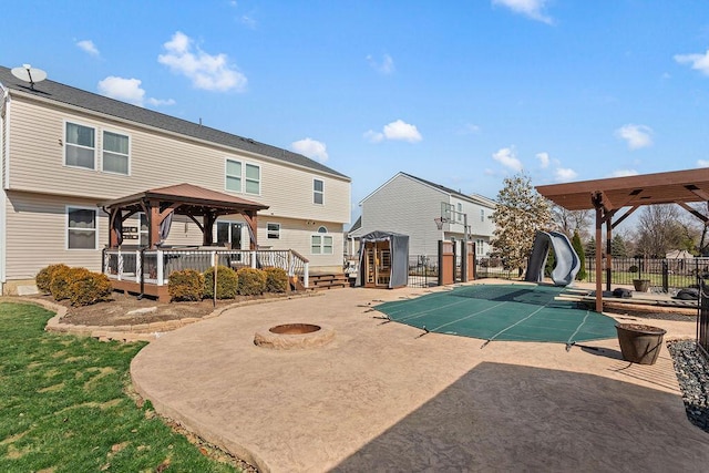 view of pool featuring a fire pit, a water slide, fence, a gazebo, and a patio