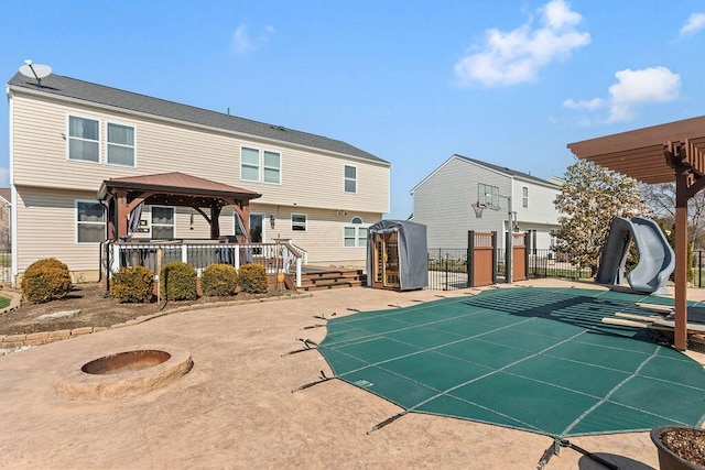 view of swimming pool featuring an outbuilding, a patio, fence, a gazebo, and an outdoor fire pit