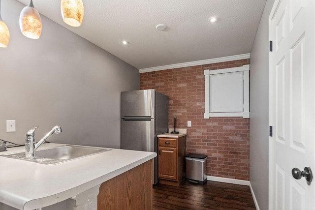 kitchen featuring dark wood-type flooring, a sink, brick wall, light countertops, and baseboards