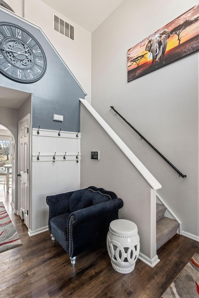 stairs featuring arched walkways, visible vents, baseboards, and wood finished floors