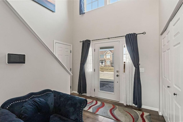 foyer entrance featuring baseboards, plenty of natural light, wood finished floors, and a towering ceiling