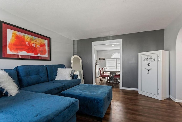 living area with wood finished floors, baseboards, and arched walkways