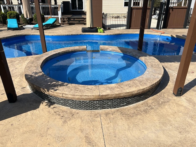 view of swimming pool with fence and a pool with connected hot tub