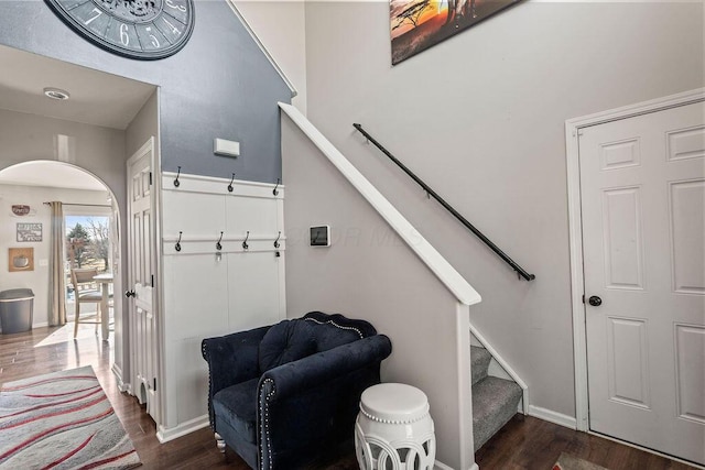 interior space with wood finished floors, arched walkways, and baseboards