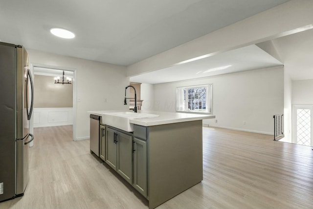 kitchen with gray cabinetry, a sink, light wood-style floors, appliances with stainless steel finishes, and light countertops