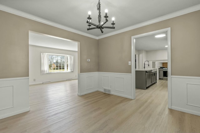 dining area featuring a wainscoted wall, light wood-style floors, visible vents, and ornamental molding