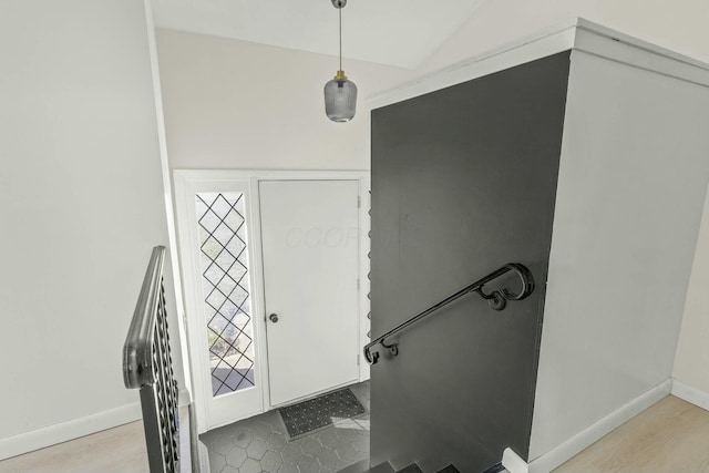 foyer featuring vaulted ceiling and baseboards