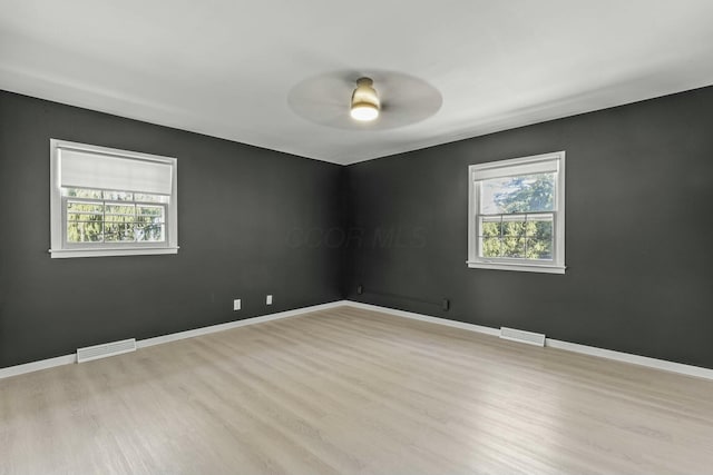 unfurnished room featuring visible vents, ceiling fan, baseboards, and wood finished floors