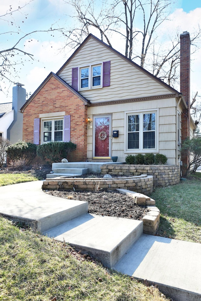 bungalow-style house with a front lawn, brick siding, and a chimney