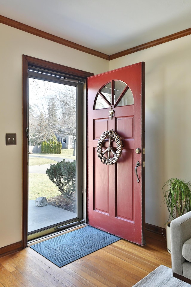 entrance foyer featuring baseboards, light wood-style flooring, and crown molding