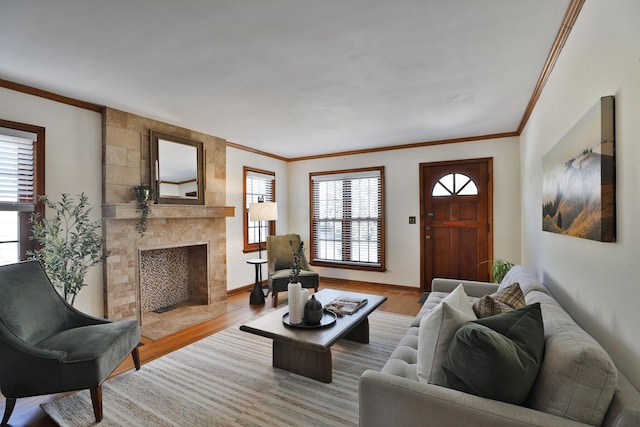 living room with a wealth of natural light, ornamental molding, a fireplace, and wood finished floors