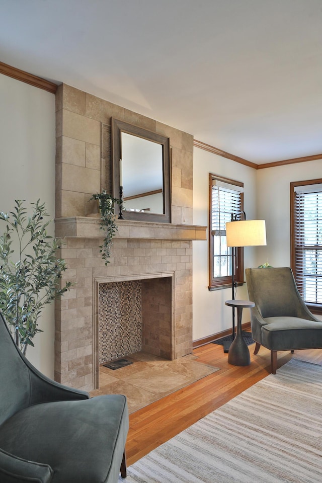 living room featuring a healthy amount of sunlight, a fireplace, crown molding, and wood finished floors