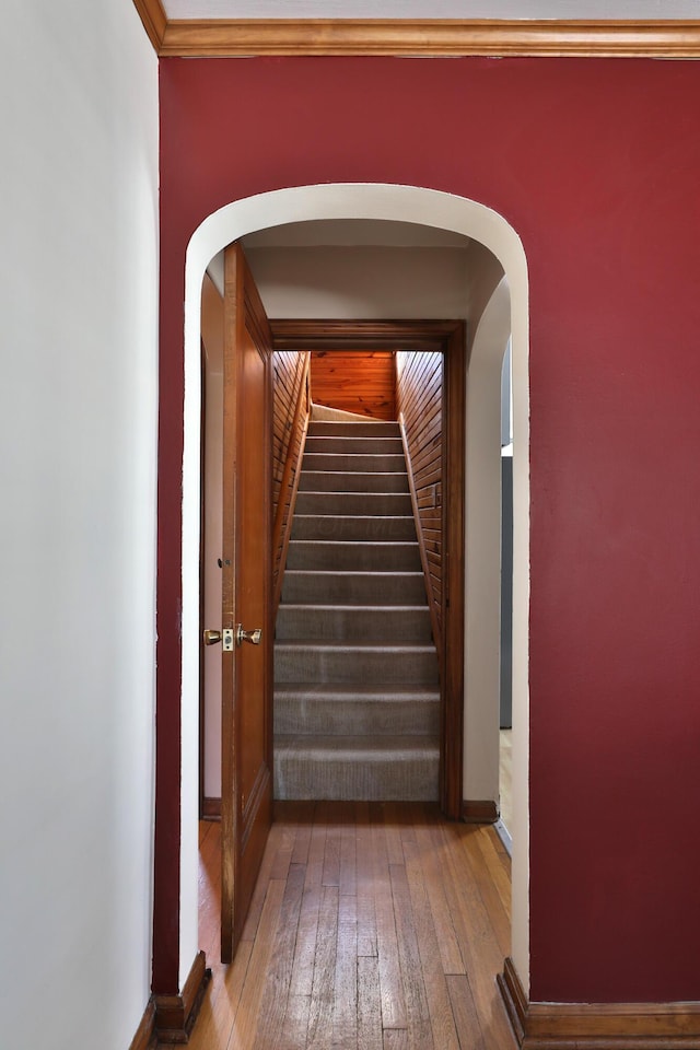 corridor with hardwood / wood-style floors, stairs, and arched walkways