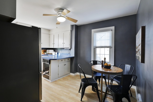 dining room featuring baseboards, light wood-style floors, and a ceiling fan