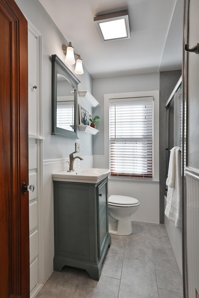 full bath with a wealth of natural light, toilet, wainscoting, and vanity