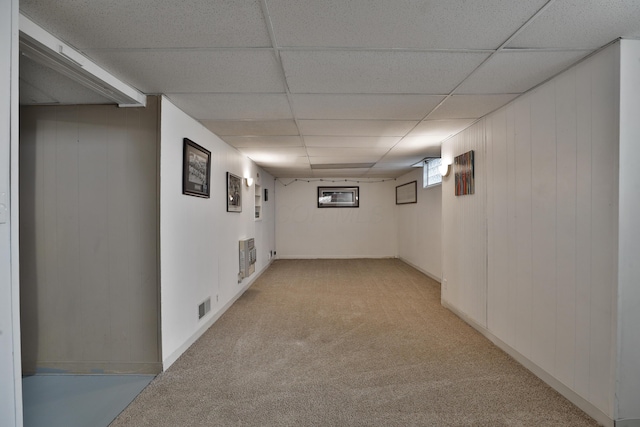 below grade area featuring light colored carpet, a paneled ceiling, and visible vents