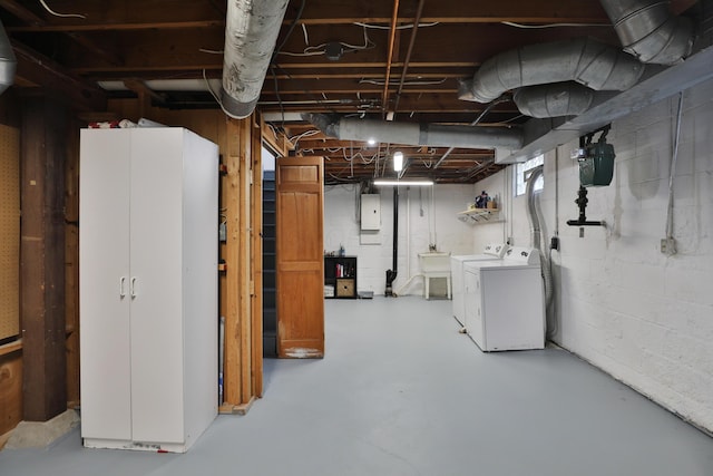 basement featuring electric panel, separate washer and dryer, and a sink