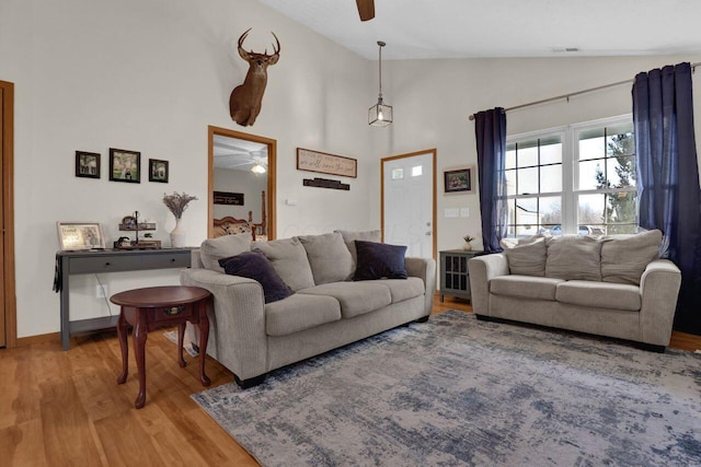 living area with a ceiling fan, visible vents, baseboards, high vaulted ceiling, and light wood-type flooring