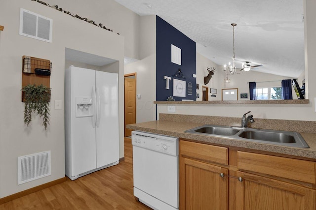 kitchen with a sink, visible vents, white appliances, and vaulted ceiling