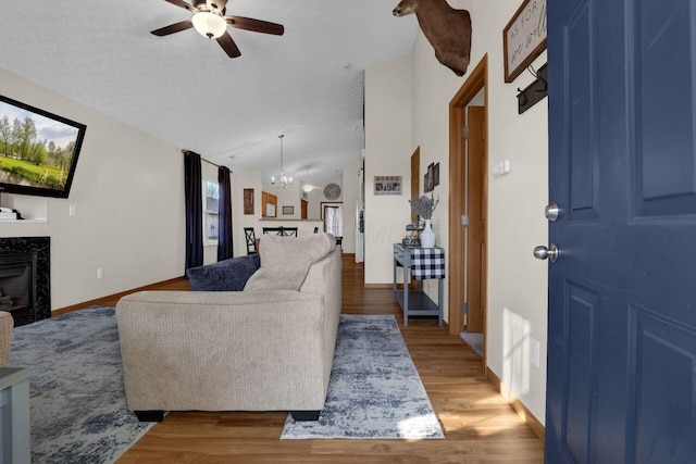 living room with a textured ceiling, light wood-style floors, lofted ceiling, and a premium fireplace