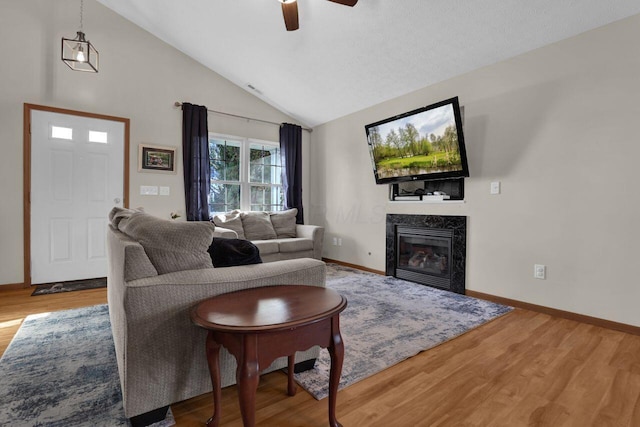 living room with baseboards, lofted ceiling, wood finished floors, and a fireplace