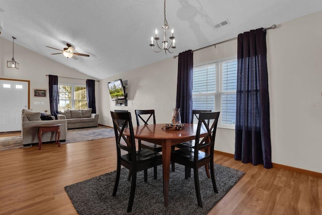 dining room featuring light wood-type flooring, visible vents, baseboards, and vaulted ceiling