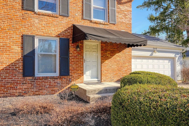 doorway to property with brick siding and a garage