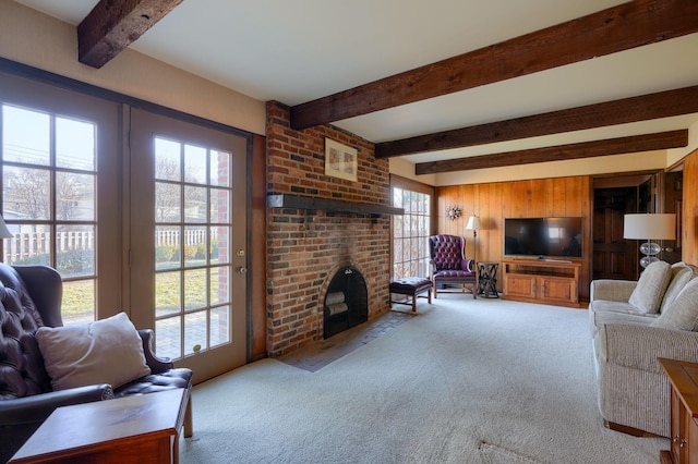 carpeted living room with beam ceiling, wood walls, and a fireplace