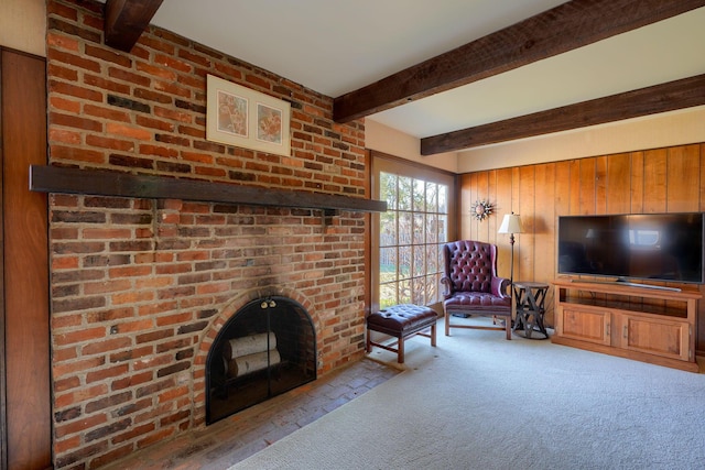 carpeted living area featuring beam ceiling, wooden walls, and a fireplace