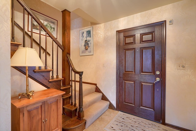 foyer entrance featuring baseboards, stairs, and wallpapered walls